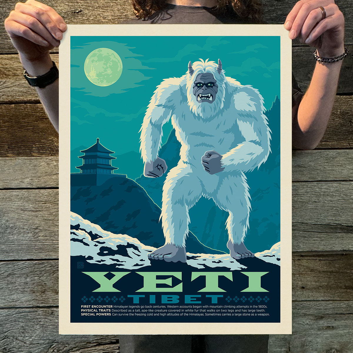 Person holding a poster of a Yeti with a mountain and moon background
