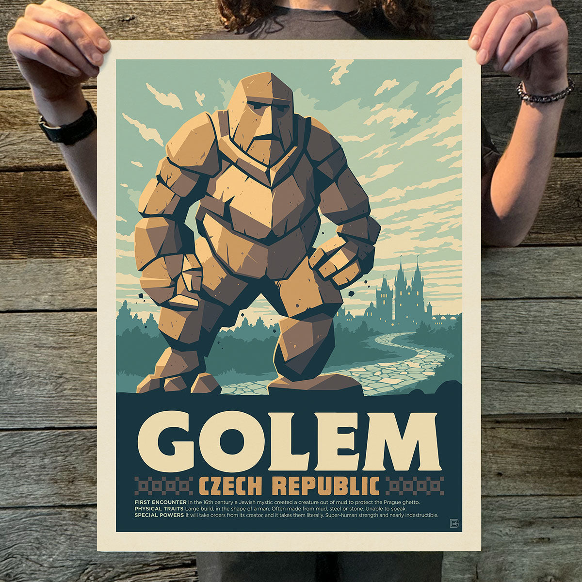 Poster of a golem with a castle in the background held by two hands on a wooden surface.