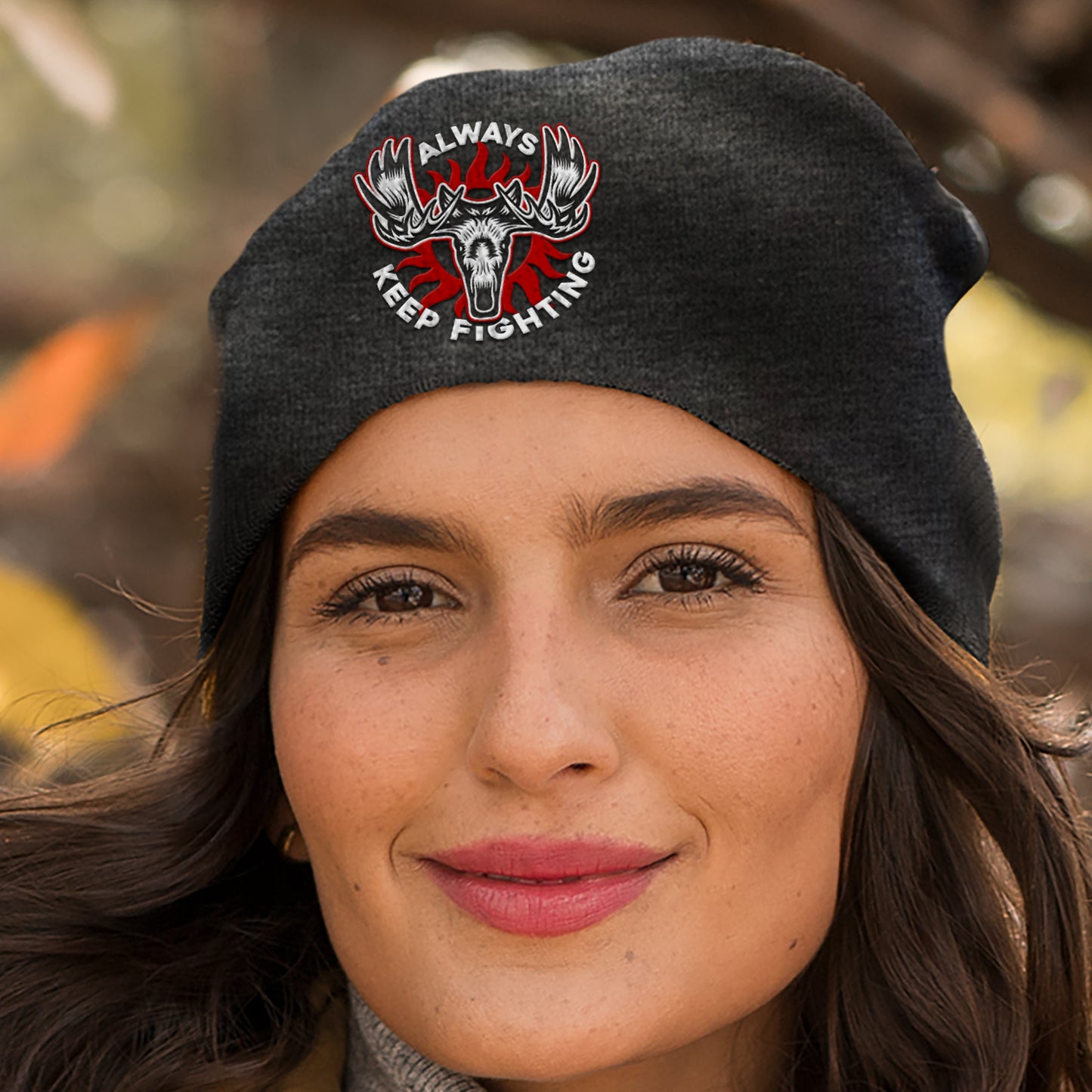 A model wearing a charcoal beanie. On the front is a depiction of a moose head, with "always keep fighting" in white text.