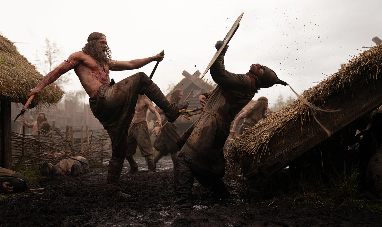 An image of a Viking warrior in battle, kicking an opponent in a field of hay.