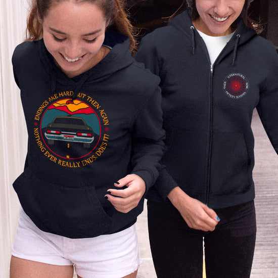 Two female models side by side. The left model is wearing a black pullover hoodie. On the front is the tail end of a black 1967 Chevy Impala driving on a black road toward a red and yellow sunset. Around the edge is yellow text saying “Endings are hard, but then again nothing ever really ends, does it?" The right model is wearing a black zip hoodie. On the right side is the anti-possession symbol in red. Around the edge of the symbol, white text says "Supernatural, Fifteen Seasons. Then... Now..."