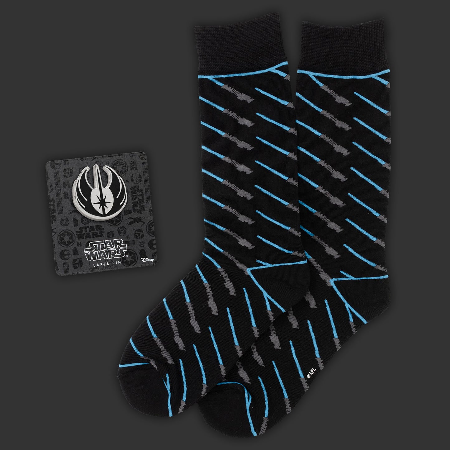 Black socks  with a repeating blue lightsaber pattern on a dark background. Next to the socks is a Jedi Crest lapel pin.