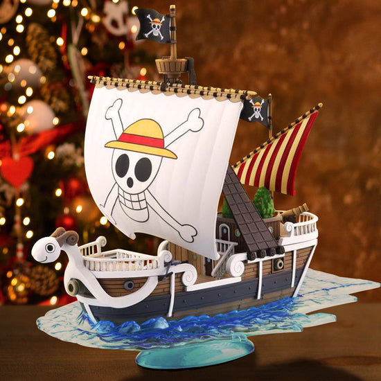 A pirate ship model from the series One Piece with skull and crossbones design, sitting on a wooden table. In the background is a decorated Christmas tree.