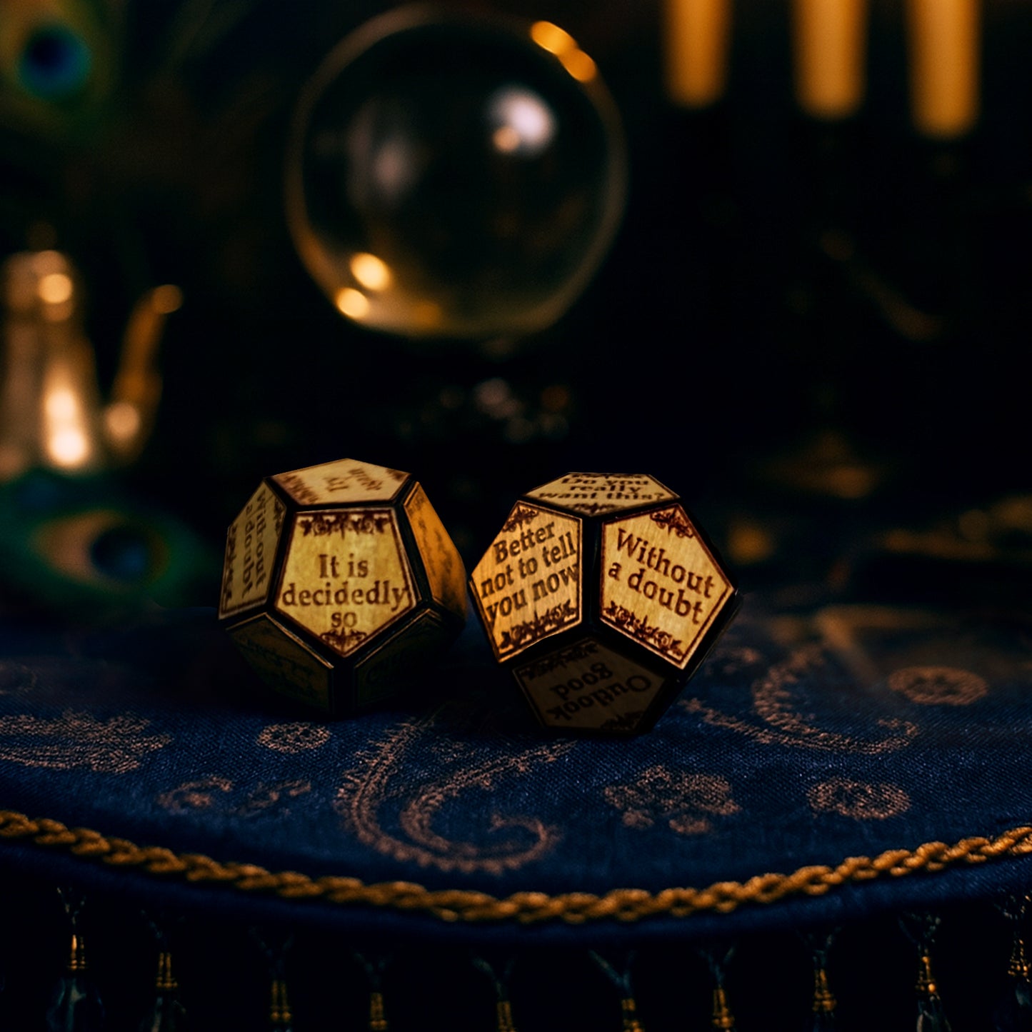 A pair of wooden 12-sided dice, with statements on each side. The statements include don't count on it, outlook good, without a doubt, and other similar sayings. The dice are on a blue fabric table cover with ornate gold decorations. In the background is a crystal ball.