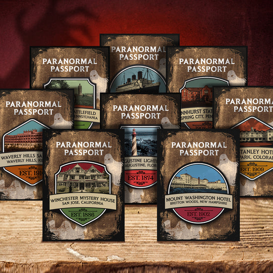 Eight enamel pins on a wooden shelf. Each pin depicts a drawing of a famous haunted location in the USA. Behind the pins is a red background, with a faint shadow of a creepy hand reaching upward