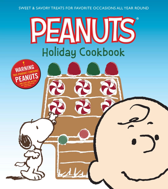 A hardcover cookbook featuring Snoopy and Charlie Brown. Snoopy is adding decorations to a gingerbread version of his doghouse. Text at the top says Peanuts holiday cookbook.