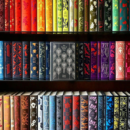 A collection of colorful books lined up on three bookshelves. In the center is a black book with white text saying "The Picture of Dorian Gray, Oscar Wilde."