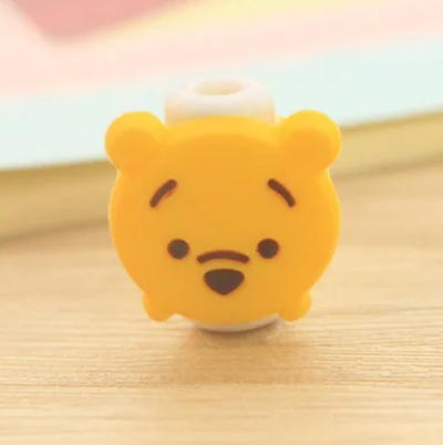 Close up view of a plastic phone charger clip, with Winnie The Pooh's face on the front.