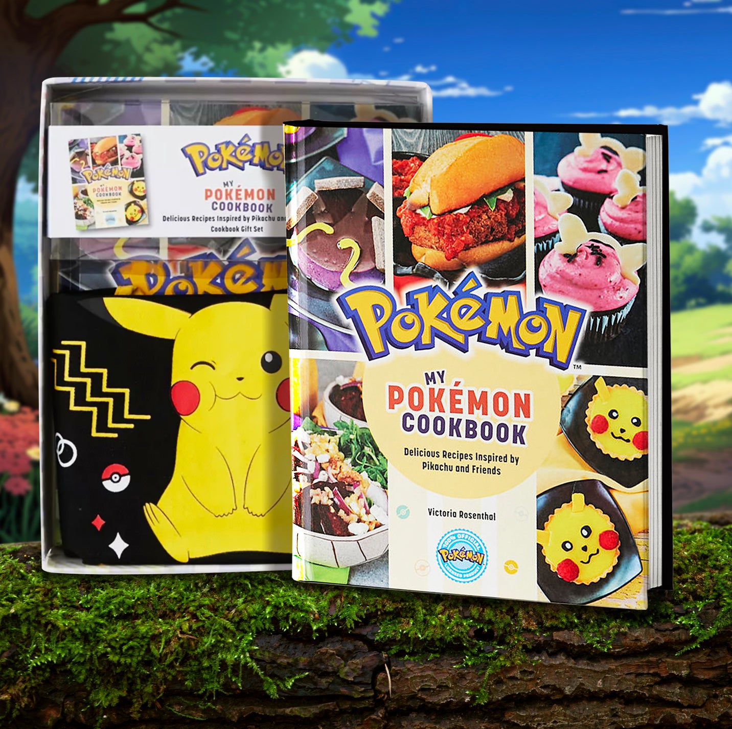 A hardcover cookbook next to a cardboard box, both standing on a moss-covered log. The book has pictures of various recipes on the cover, with text saying "Pokemon, my Pokemon cookbook." Inside the cardboard box is a folded black and yellow apron, with a Pikachu printed on the front. In the background is a meadow with trees and flowers.