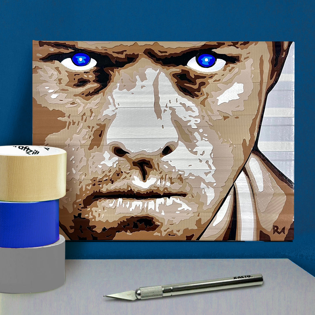 A poster on a blue wall, made of layered pieces of duct tape, depicting the angel Castiel with glowing blue eyes. In front of the poster is an X-acto knife and rolls of duct tape.