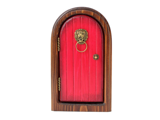 An arched wooden doorframe with a red door, against a white background. At the sides of the door are brass hinges. A brass doorknob sits at the right side, and a lion-head shaped knocker with a hood is at the top of the door.