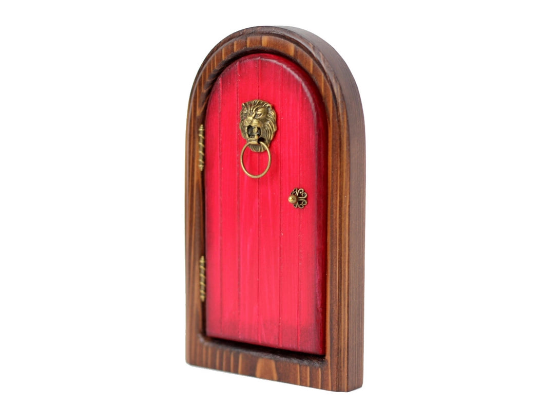 An arched wooden doorframe with a red door, against a white background. At the sides of the door are brass hinges. A brass doorknob sits at the right side, and a lion-head shaped knocker with a hood is at the top of the door.