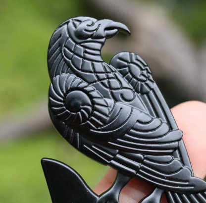 Close up image of a black hair pin, with a raven-shaped top.