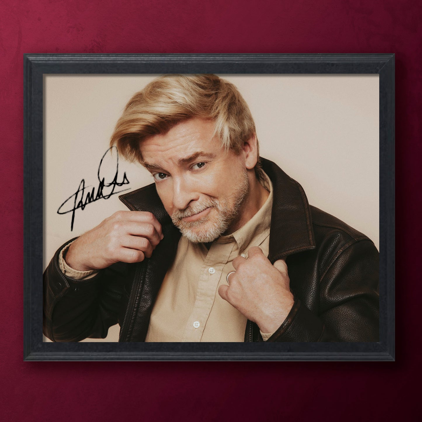 Framed photograph of Rhys Darby with a signature on a beige background