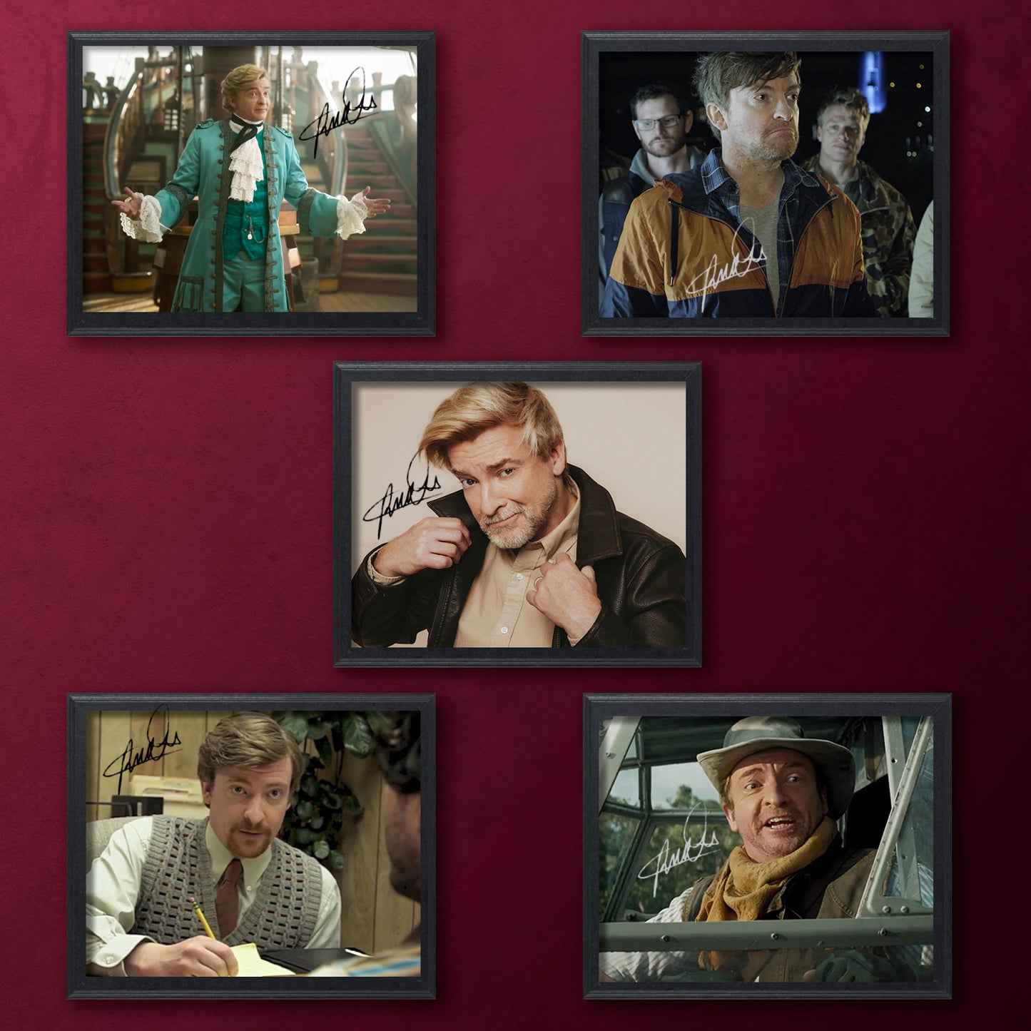 Framed photos of actor Rhys Darby in various outfits on a red wall.