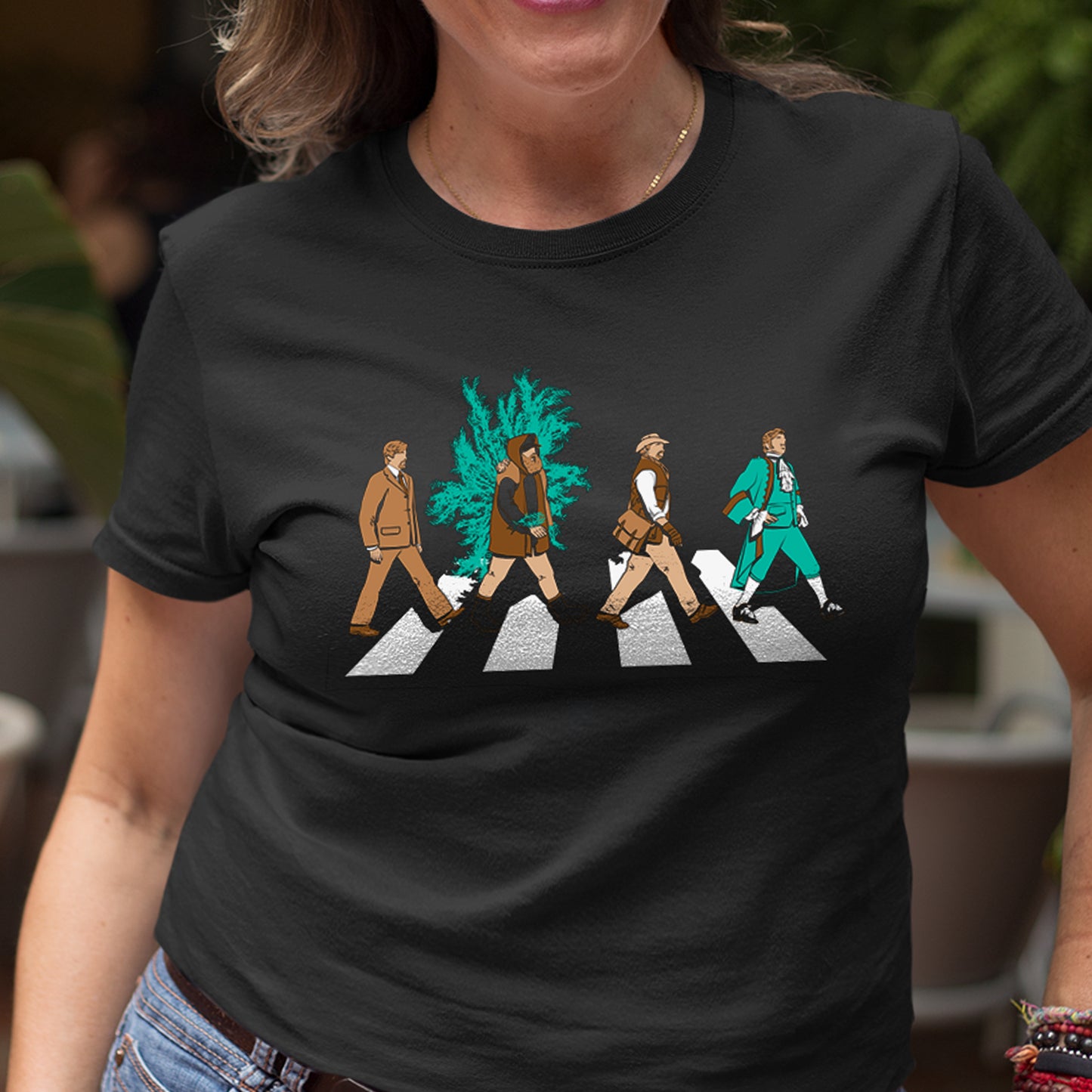 A model wearing a black t-shirt. On the front are four characters crossing a street, mimicking the iconic Beatles Abbey Road image
