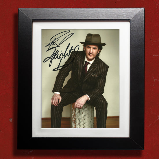 A black framed photograph against a dark red wall. The photograph depicts actor Richard Speight, Jr, in a black pinstripe suit and fedora hat. In the top left corner is Richard's autograph in black ink.