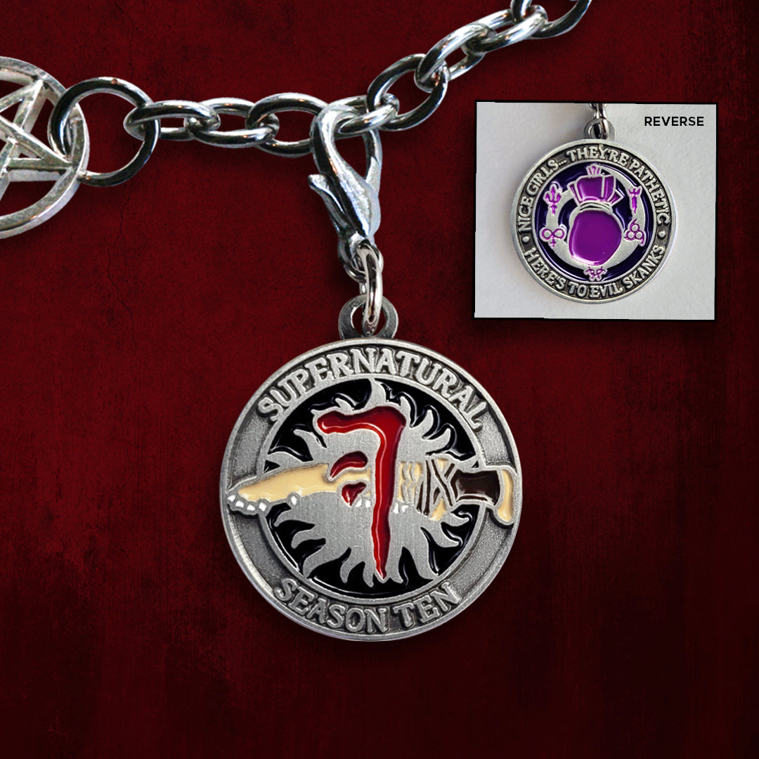 A brass coin with "Supernatural season ten”, The front has a black background, and the anti-possession symbol with a knife piercing it, with the Mark of Cain on top. The back has “Nice’ girls… they’re pathetic. Here’s to evil skanks” printed around the edge.”, and a purple spell bag with spell symbols surrounding it