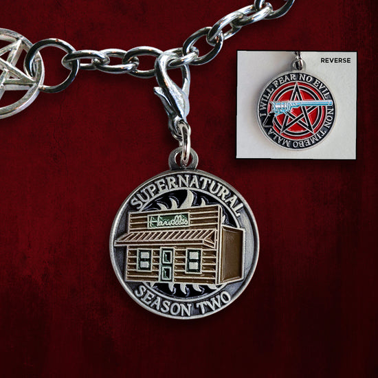 Front and back of a brass charm. On the front is brown pub with a green door, reading "SUPERNATURAL SEASON TWO". On the back is a blue colt revolver against a red and blue pentagram, reading "I WILL FEAR NO EVIL / NON TIMEBO MALA". Behind the charms is a red wall.