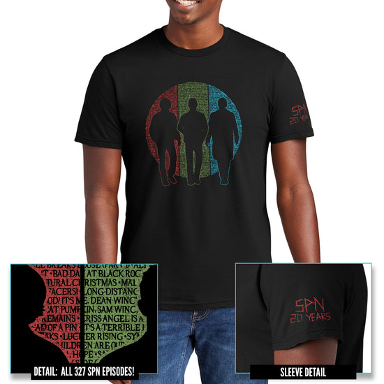 A male model wearing a black crew neck shirt. The shirt features silhouettes of Sam and Dean Winchester and Castiel. Behind them is a circle split into vertical thirds - a red slice behind Sam, green behind Dean, and blue behind Castiel. The circle is filled with the titles of all 327 episodes of Supernatural in black font. One short sleeve reads 'SPN 20 YEARS' in a capital font with a 'carved' effect.