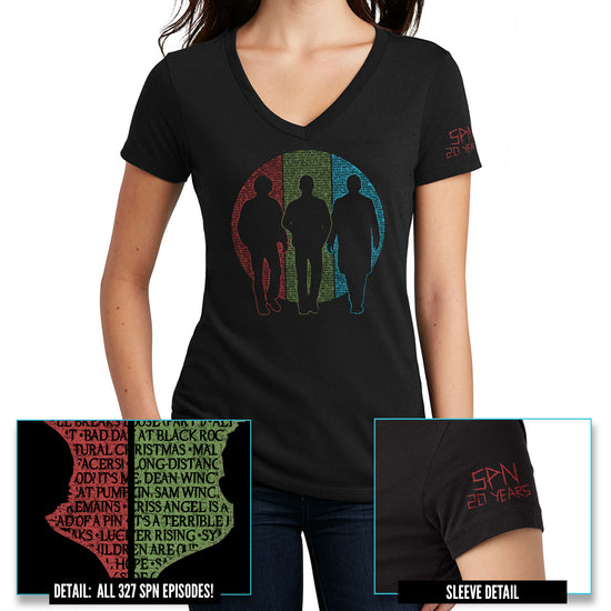 A female model wearing a black v-neck shirt. The shirt features silhouettes of Sam and Dean Winchester and Castiel. Behind them is a circle split into vertical thirds - a red slice behind Sam, green behind Dean, and blue behind Castiel. The circle is filled with the titles of all 327 episodes of Supernatural in black font. One short sleeve reads 'SPN 20 YEARS' in a capital font with a 'carved' effect.