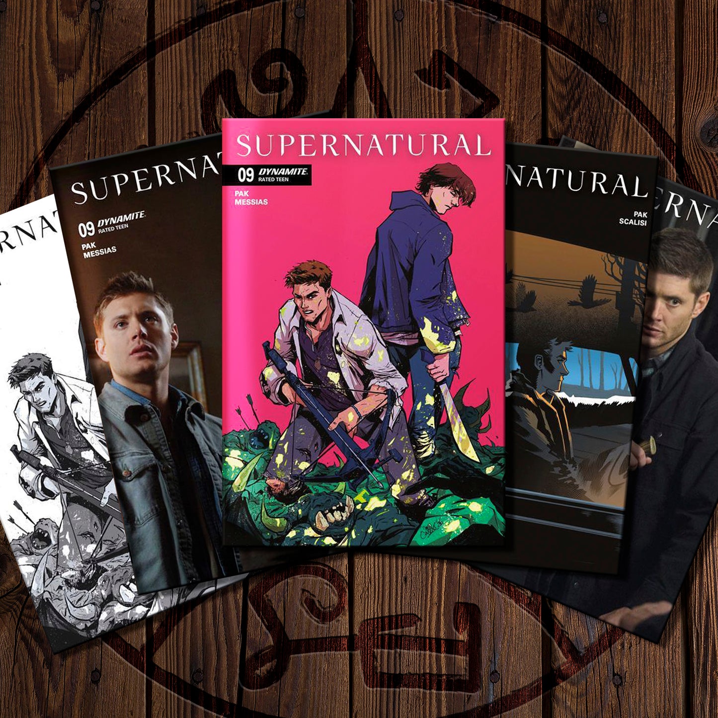 A fan arrangement of four Supernatural comic book issues on a dark wood background. The center issue is a bright pink cover featuring illustrated characters, flanked by other covers including character art and title text.