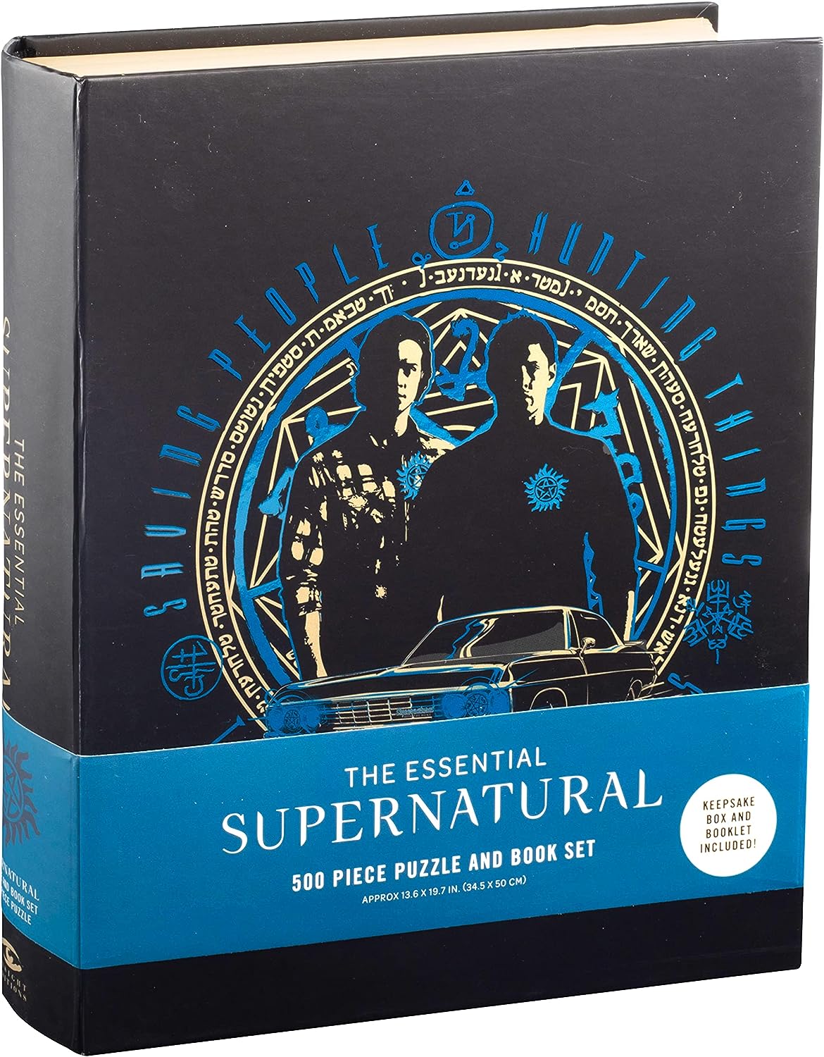 A black book on a white background. On the cover is a white and blue drawing of Sam and Dean Winchester, inside a circle with runes around the edge. Under them is a drawing of Baby. At the bottom is a blue banner with white text saying "The essential supernatural 500 piece puzzle and book set."