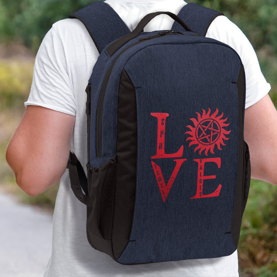 Close up of a dark blue backpack on a model's shoulders. The backpack has the word "Love" in a square shape, in red text. The "O" is replaced with the anti-possession symbol.