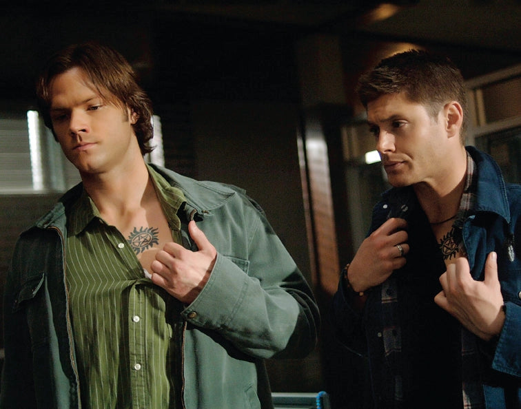 An image of Sam and Dean Winchester revealing their Anti-Possession symbol tattoos.