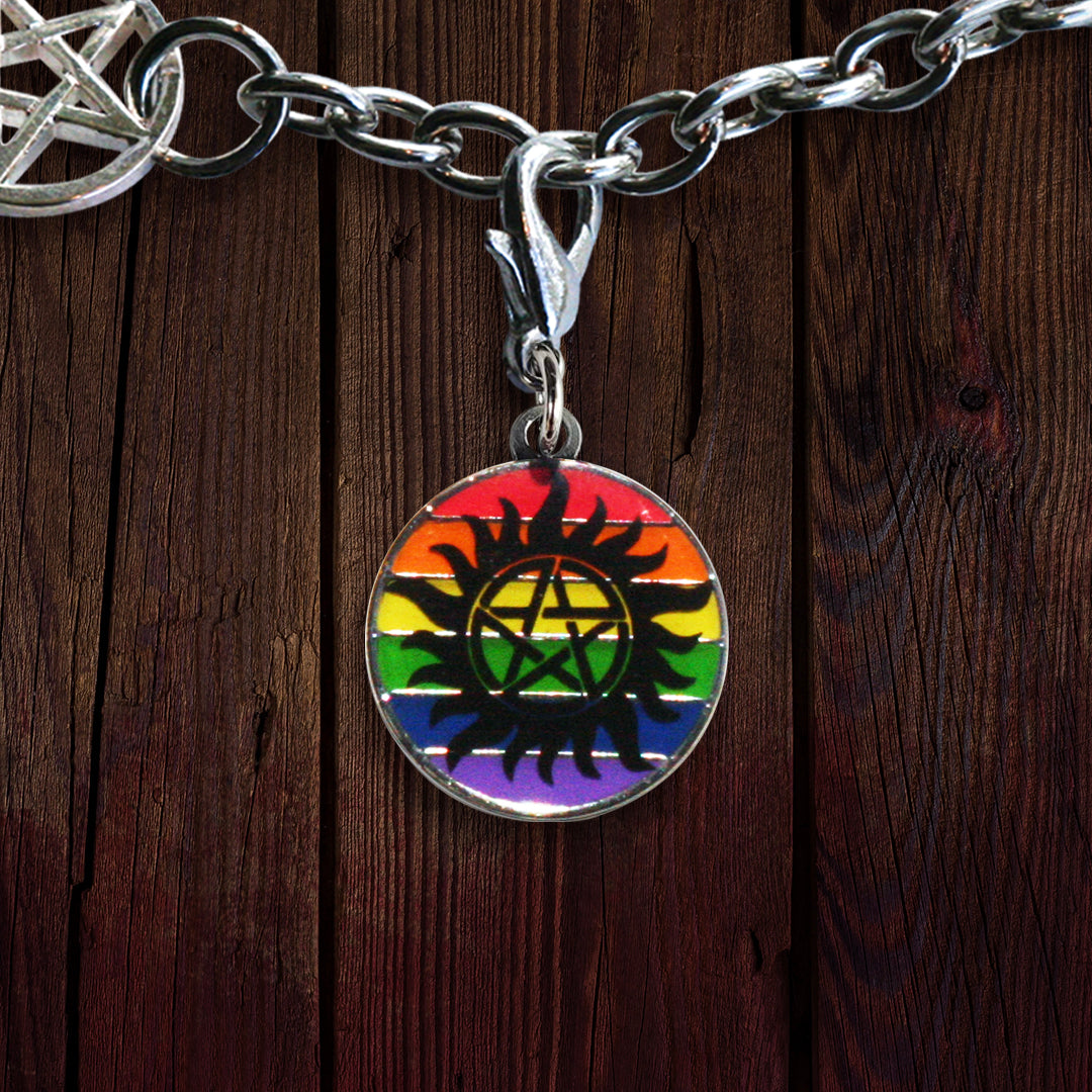 A brass charm with rainbow stripes, and the anti-possession symbol in black, against a wood background.