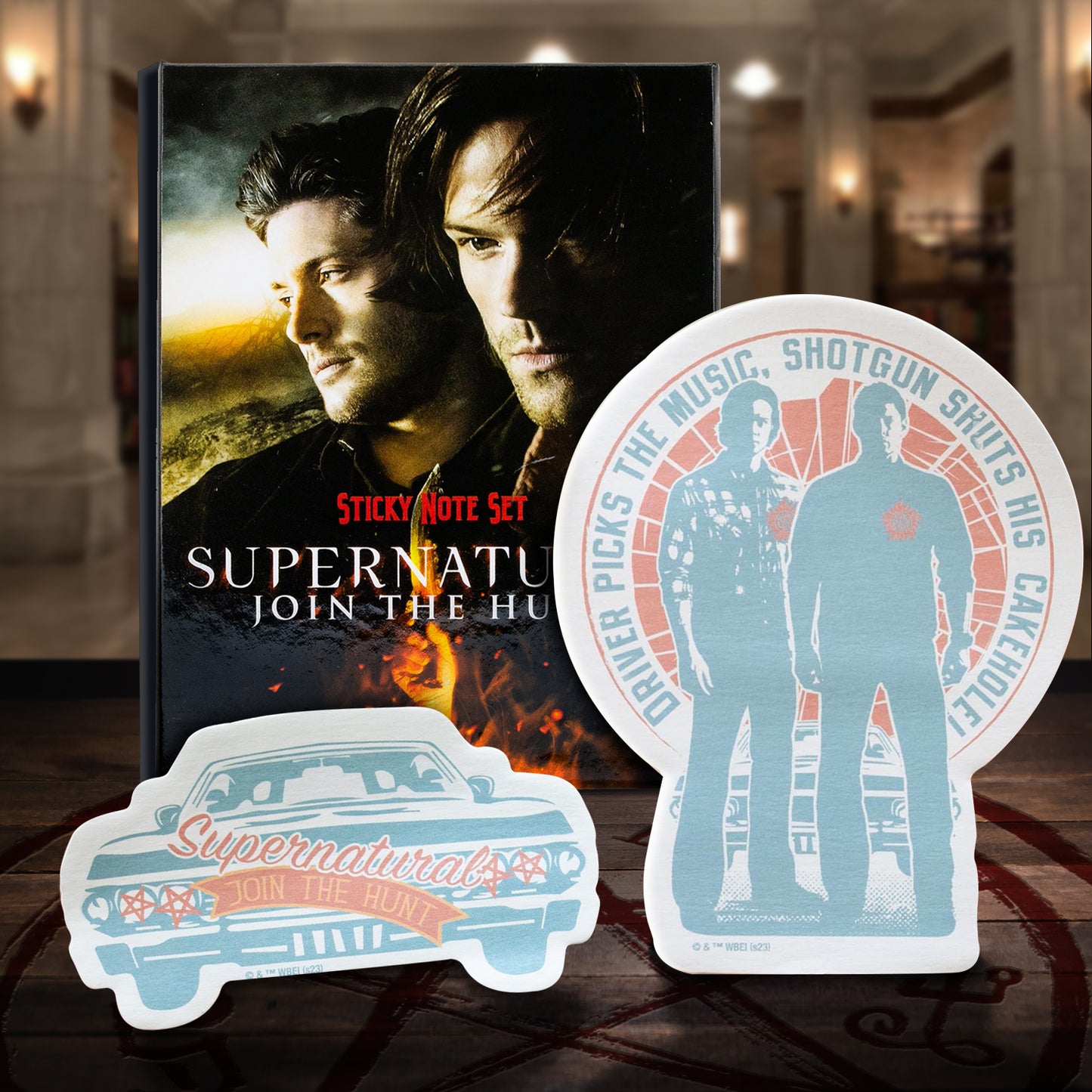 A sticky note box set featuring Sam and Dean Winchester on the front. Red and white text says Supernatural, Join The Hunt, sticky note set. In front of the box are two SPN-themed sticky notes