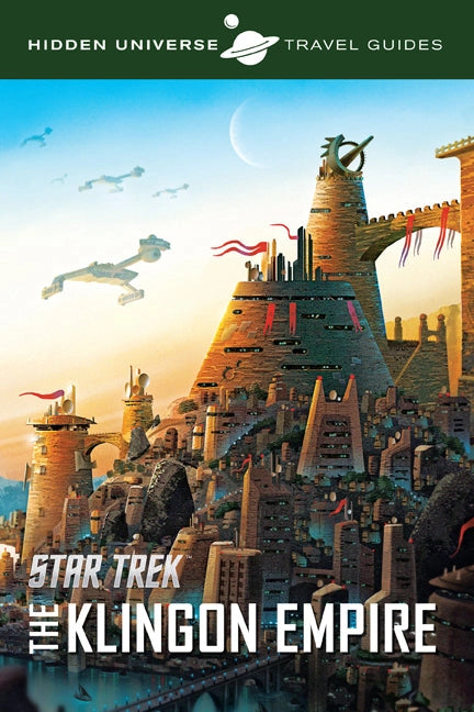 A travel guide book against a white background. The cover depicts a Klingon city from the Star Trek universe. Tan stone buildings with red banners are clustered in the middle. Several Klingon warships are in the sky. At the top is a green banner with white text saying "hidden Universe Travel Guides," and a drawing of the planet Saturn sits in the center. At the bottom is white text saying "Star Trek: The Klingon Empire." Behind the book is a Klingon city.