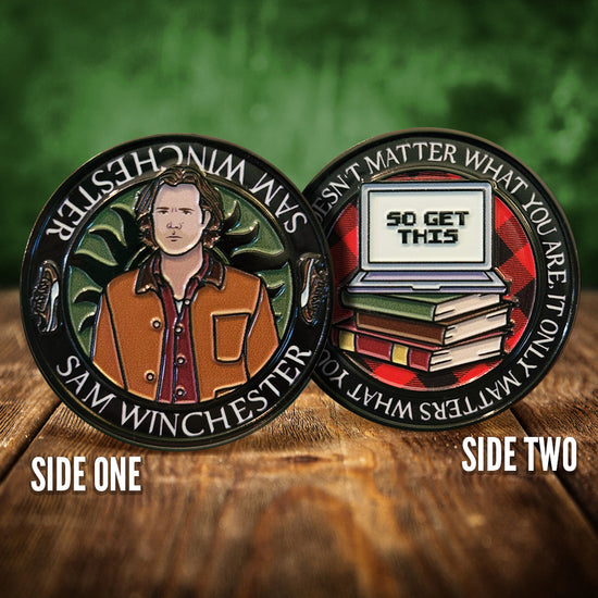 Front and back images of a challenge coin, side by side, on a wood table. The front depicts a drawing of Sam Winchester, wearing a brown jacket. Behind him is the edge of the anti-possession symbol. The back of the coin depicts a laptop on a stack of books, with text on the laptop screen that says "So get this." White text around the edge says "It doesn’t matter what you are, it only matters what you do"