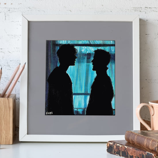 A painting mounted on a gray background in a white frame. The painting shows the silhouettes of Dam and Dean Winchester, facing each other in front of an open window. Behind the painting is a white brick wall.