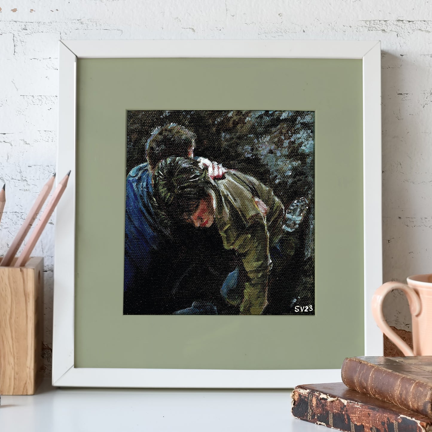 A painting mounted on a green background in a white frame. The painting shows Sam and Dean Winchester embracing each other in a dark forest. Behind the painting is a white brick wall.