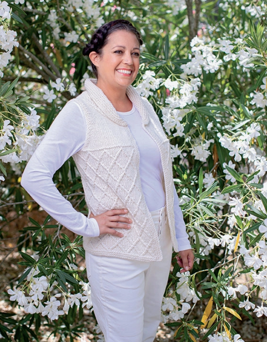 A woman standing in front of a plant with white flowers. She is wearing a knit white sweater, fashioned to resemble Princes Leia’s costume from the conclusion of the first Star Wars movie.