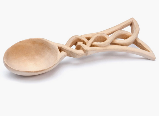 A carved wooden spoon on a white background. The spoon's handle is shaped much like a Celtic knot pattern.