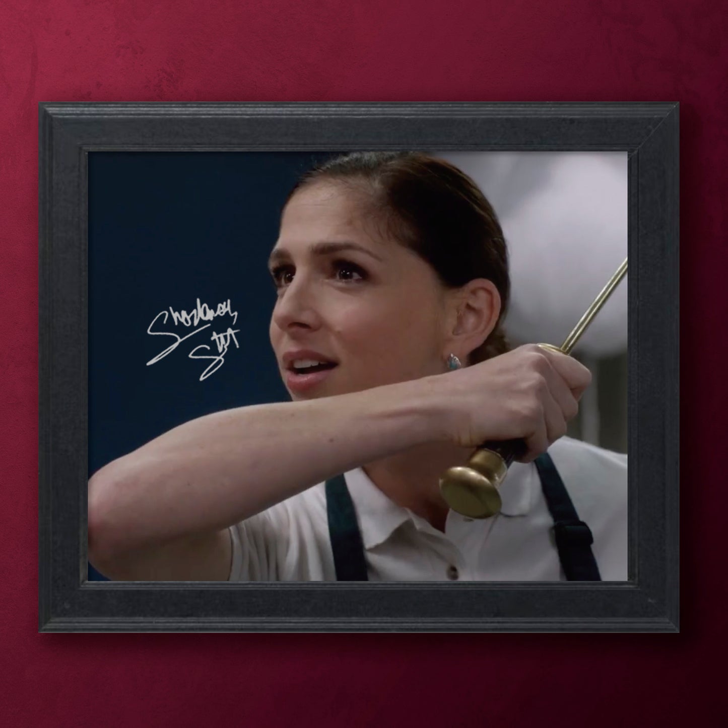 Framed photograph of a SPN character Eileen holding a dagger with a signature, against a red background