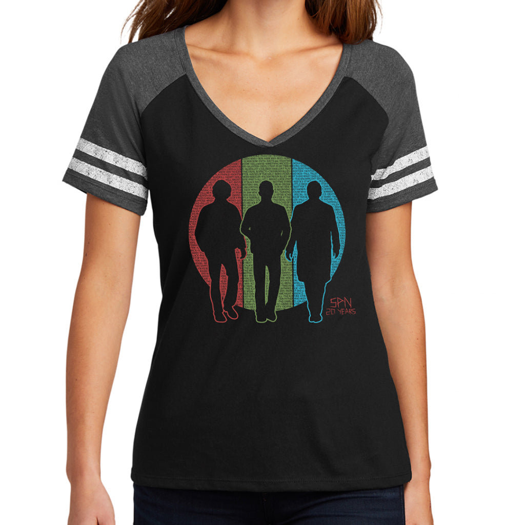 A female model wearing a black v-neck shirt and grey sleeves. The shirt features silhouettes of Sam and Dean Winchester and Castiel. Behind them is a circle split into vertical thirds - a red slice behind Sam, green behind Dean, and blue behind Castiel. The circle is filled with the titles of all 327 episodes of Supernatural in black font.