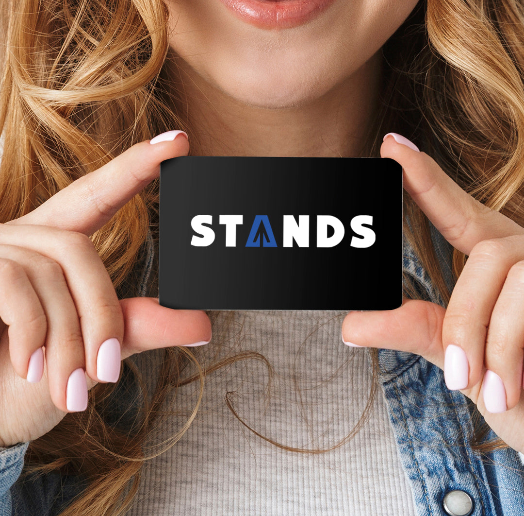 Close up of a female model holding a black gift card. On the front of the card is the Stands logo in white and blue.