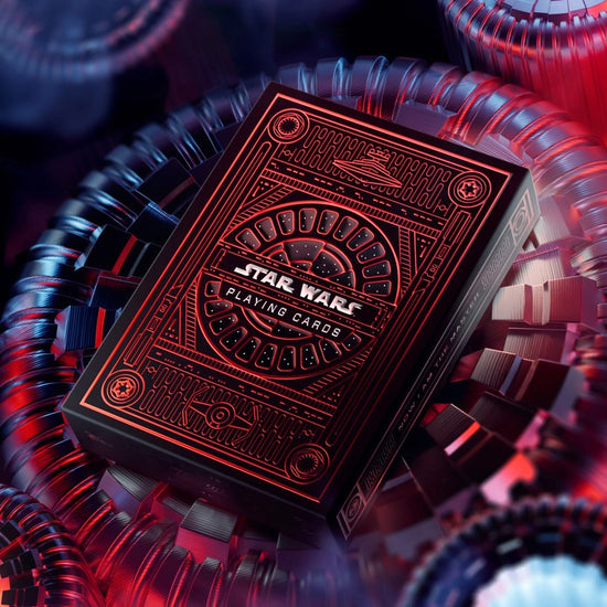 A red and black box of playing cards on a red metal surface. The box depicts images from the Star Wars franchise.