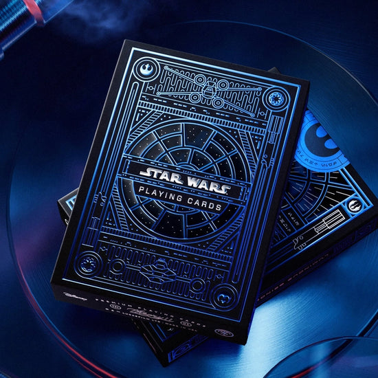 A blue and black box of playing cards on a blue metal surface. The box depicts images from the Star Wars franchise.