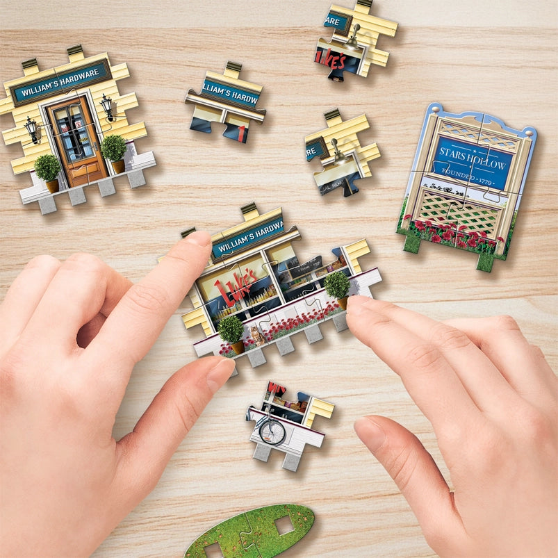 Jigsaw puzzle pieces depicting Stars Hollow from the TV series "Gilmore Girls," with a model's hand putting the pieces together.