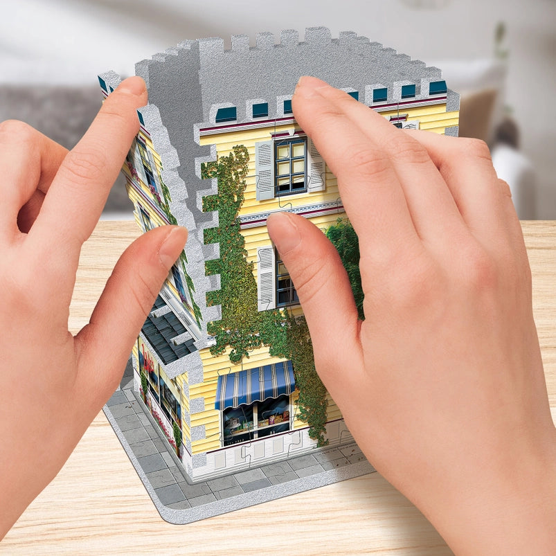 Jigsaw puzzle pieces depicting Stars Hollow from the TV series "Gilmore Girls," with a model's hand putting the pieces together.