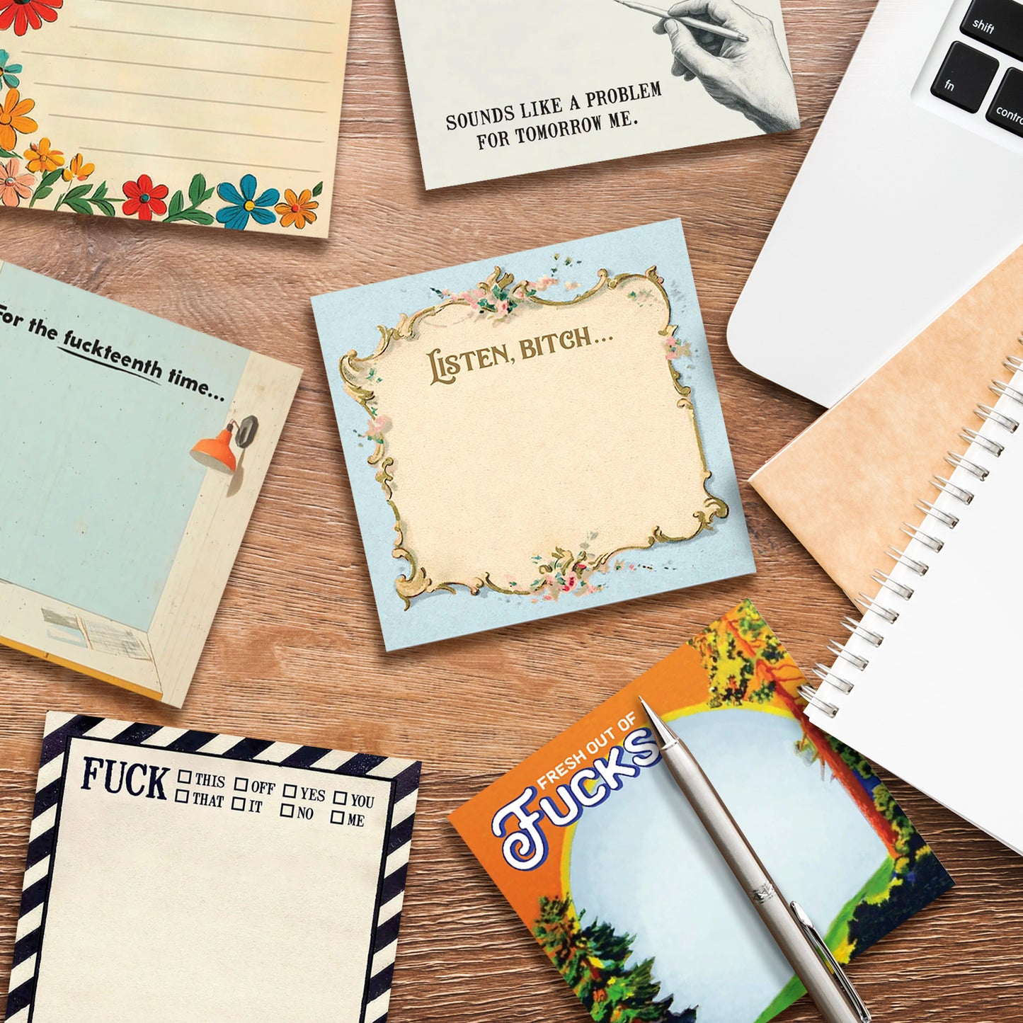 A collection of sticky note pads on a desk. At the top of each pad is a different profane phrase