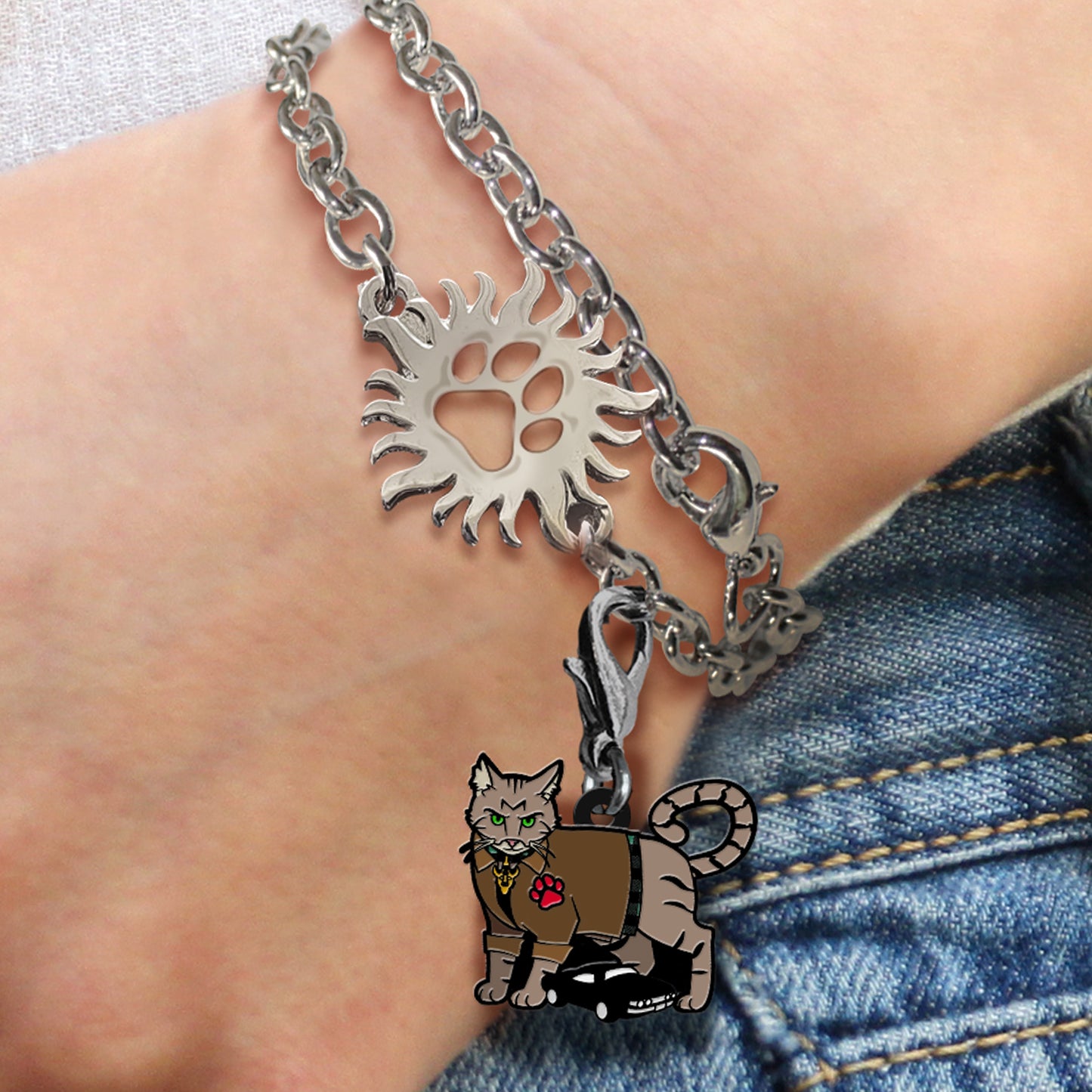 Bracelet with sun charm and cat pendant on a wrist against a denim background