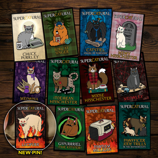 A collection of enamel pins on a wooden table. Each pin depicts a character from the TV series "Supernatural" reimagined as cats. An inset in the bottom left corner reads "NEW PIN!" and has an image of Lucifurr, the newest pin.