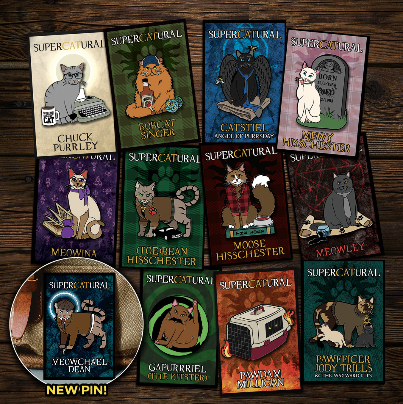 A collection of enamel pins on a wooden table. Each pin depicts a character from the TV series "Supernatural" reimagined as cats. An inset in the bottom left corner reads "NEW PIN!" and has an image of Meowchael Dean, the newest pin.