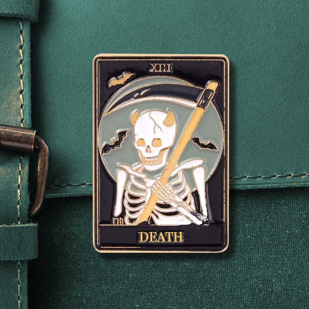A rectangular tarot pin that reads "XIII" on the top and "DEATH" on the bottom, in gold. The pin depicts a skeleton holding a scythe, in front of a full moon, surrounded by 3 small bats.