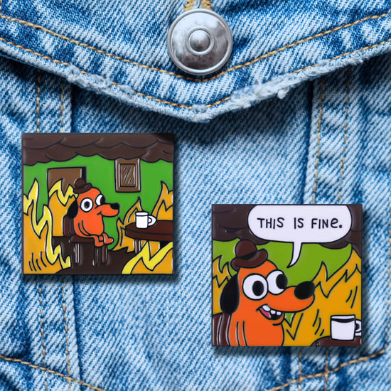 Two enamel pins on a blue denim shirt. Each pin depicts an orange dog sitting at a table, smiling as the room around his is engulfed in flames. In one pin is a white caption bubble, with black text saying "This is fine."